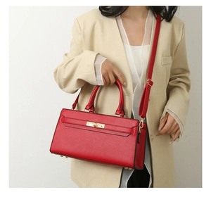 Detail of red pebbled leather tote with gold twist lock on beige blazer model