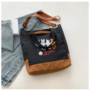 Detail of cute cat print tote bag featuring a brown shoulder strap and contrast bottom