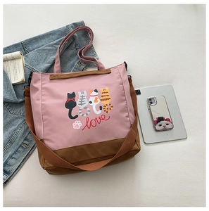 Flat lay of pink canvas tote bag with cat print, tablet, and books for casual daily use