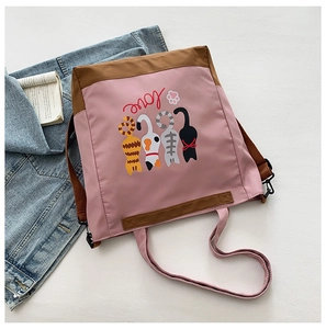Detailed view of tote bag featuring cute cartoon cats and pink canvas shoulder strap