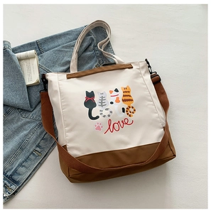 Detail of cartoon cat prints on minimalist cream tote bag with brown adjustable strap