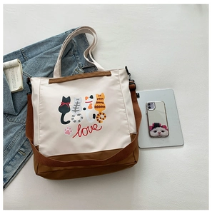 Detail of cute cat print tote bag with adjustable brown strap and canvas texture