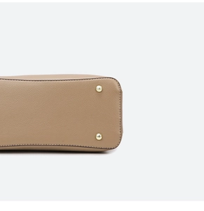 Detail of khaki pebbled leather bag bottom with gold metal studs and precise stitching