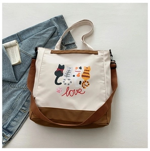 Detail of canvas tote bag with cartoon cats print and dual brown shoulder straps