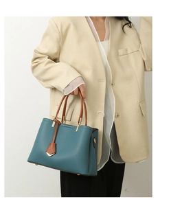Detailed close-up of blue pebbled leather tote with brown handles and gold hardware