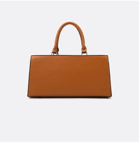 Macro detail of caramel pebbled leather texture and metal rivets on rectangular handbag