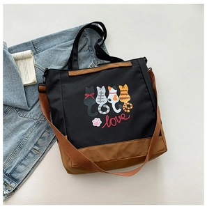 Detail of the cat print tote bag featuring black canvas and brown adjustable straps