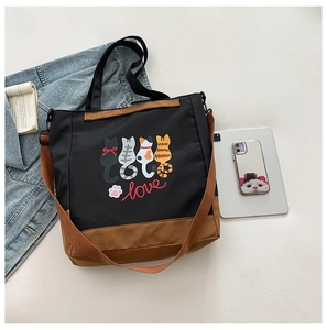 Detail showing large canvas tote bag with cartoon cat print and dual shoulder straps