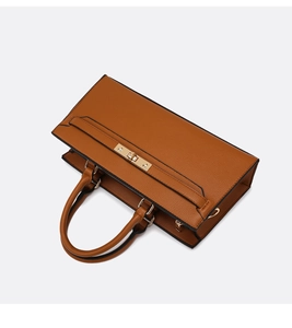 Close-up of brown lychee leather handbag with golden metal twist lock and dual handles