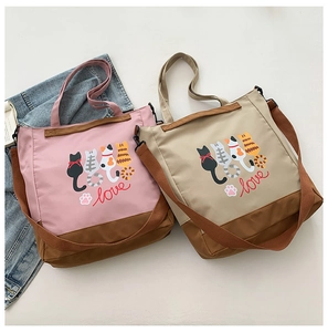 Detail view of pink and khaki cartoon cat tote bags with adjustable wide shoulder straps