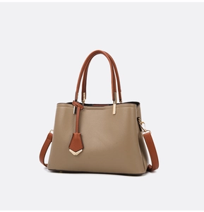 Close-up of khaki and brown pebbled leather texture with gold-tone hardware and thick handles