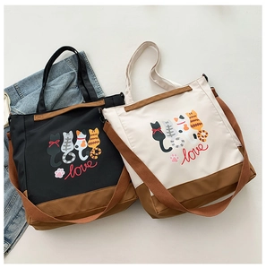Detail view of two canvas tote bags with cartoon cat prints and adjustable straps