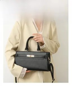 Classic black pebbled leather handbag with gold twist lock hardware and model hand display