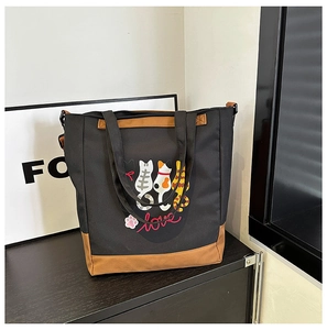 Detail of cute cat print on black canvas tote bag with brown faux leather trim