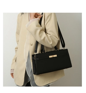 Close-up of black leather shoulder bag featuring elegant gold twist lock and dual straps