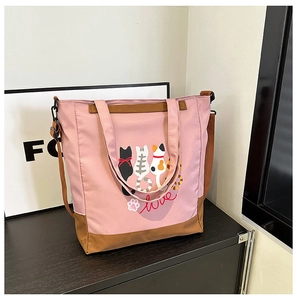 Close-up of pink and brown canvas tote bag featuring cute cartoon cat prints and love text