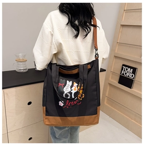 Detail of canvas tote bag with cartoon cat print and brown leather handle contrast