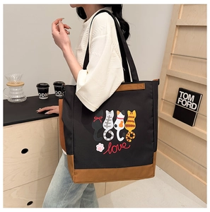 Close-up of cute cartoon cat prints on a black and brown canvas tote bag