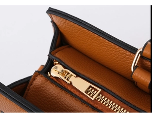 Close-up of brown pebbled leather texture and embossed gold zipper detail on handbag