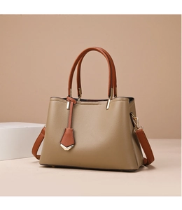 Detail view of khaki pebbled leather tote with brown straps and gold metal hardware