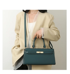 Detail of dark green pebbled leather tote bag featuring gold hardware and flap lock