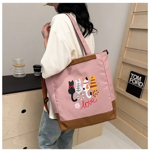 Close-up of pink canvas tote bag with cartoon cats and love text in a cozy setting