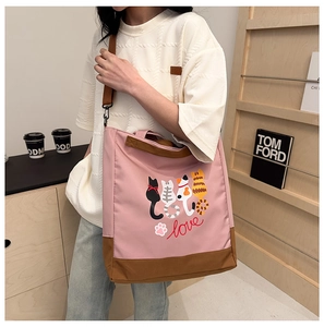 Detail of pink and brown tote bag featuring cartoon cat prints and adjustable shoulder strap