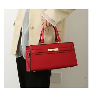 Detailed shot of red lychee textured leather tote bag featuring gold hardware and handle