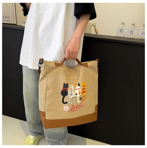 Detail of a khaki tote bag featuring cute cartoon cats and love script with sturdy handles