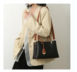 Black pebbled leather tote bag with brown straps shown on shoulder for capacity check
