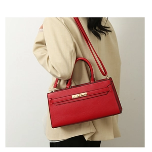 Detail of red pebbled leather shoulder bag with golden metallic clasp on beige blazer