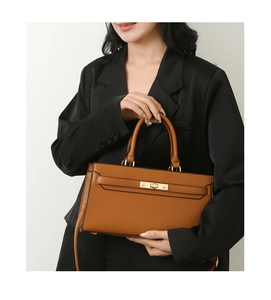Detail of brown litchi leather handbag with gold twist lock shown on a model