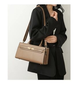 Detail of mocha brown pebbled leather tote bag with gold twist lock on black suit