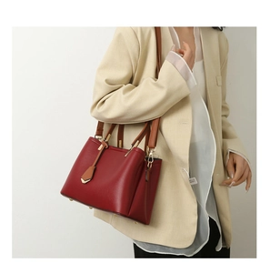 Burgundy faux leather tote bag with brown straps styled on a beige suit for workwear