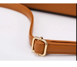 Close-up of brown lychee grain leather strap with polished gold adjustable metal buckle