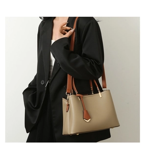 Close-up of minimalist khaki lychee leather tote bag with brown straps on model
