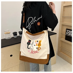 Close-up of a large canvas tote bag with cat silhouettes and shoulder strap detail