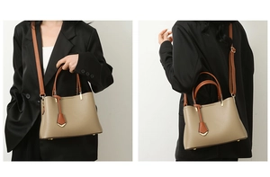 Detail view of large beige tote bag with brown straps and golden metal hardware