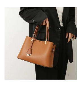 Detail of a brown lychee pattern leather tote bag with gold hardware and a side D-ring