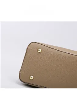 Detail view of gold metal protective feet and pebble leather texture on handbag base