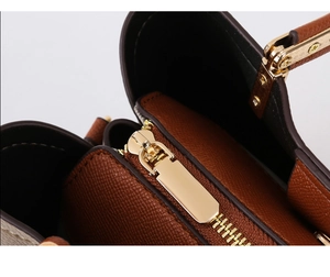 Detail shot of golden metal zipper and brown litchi pattern leather on the handbag