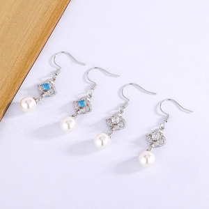 Detail of clover drop earrings with blue and clear stones and hanging white pearls