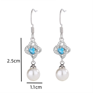 Detail view of silver earrings with sapphire blue stone and white pearl drops