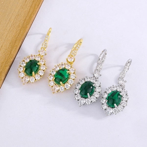 Detail of emerald green oval drop earrings in gold and silver finish with crystal halo