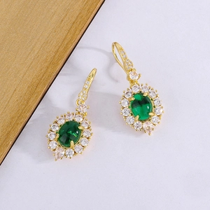 Detail of vintage emerald earrings with gold plating and teardrop zircon accents