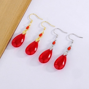 Detailed close-up of vintage red teardrop earrings in gold and silver metal finishes