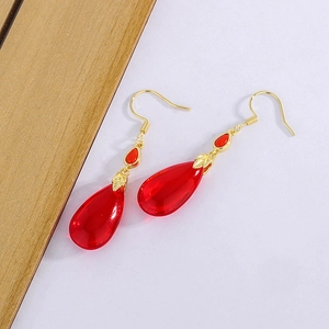 Detail of red teardrop carnelian earrings with golden leaf zircon accents and vintage design