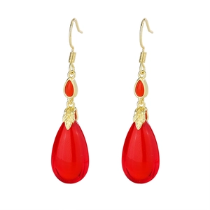Detail of red teardrop earrings with golden leaf motifs and sparkling zircon accents