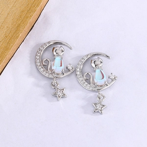 Gros plan de boucles d'oreilles chat sur croissant de lune avec opale et étoile