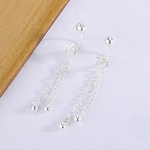 Detail of silver crown piercing with dual tassel chains and spherical bead accents